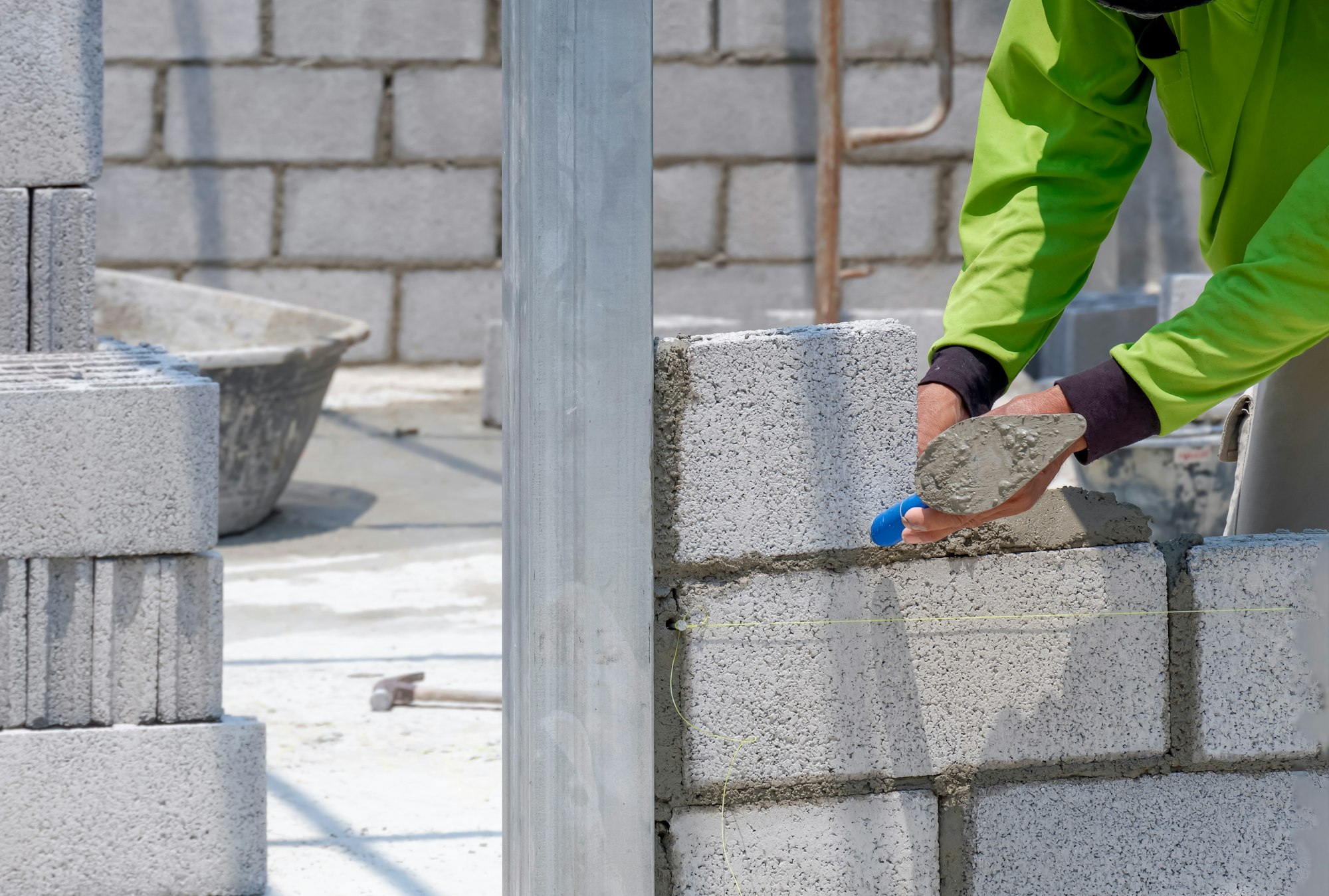 Bricklayer hand using trowel to making brick wall inside of house construction site