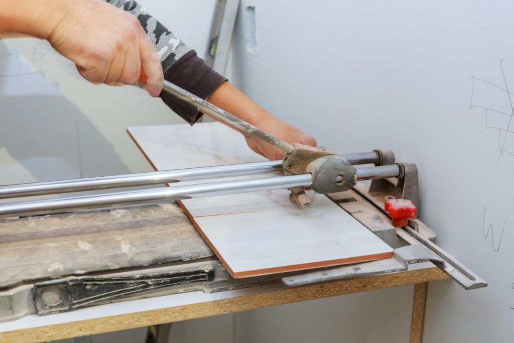 Manual cutting of ceramic tiles on a special machine for cutting tiles. Background blur